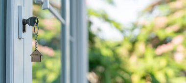 Evin kilidini açmanın anahtarı kapıya takılı. Kira ve satış için ikinci el ev. Anahtarlık rüzgarda savruluyor. Yeni ev için ipotek, satın alma, satma, yenileme, yatırım, sahip, mülk