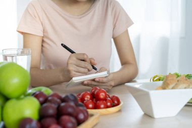 Diyet ve diyet. İnce bir kadın vücudu diyet planı yazıyor ve kalorileri sağlıklı yiyecekler için kontrol ediyor. kilo kaybı, denge, kontrol, yağ kaybı, düşük kalori, rutinler, egzersiz.