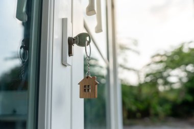 Landlord key for unlocking house is plugged into the door. Second hand house for rent and sale. keychain is blowing in the wind. mortgage for new home, buy, sell, renovate, investment, owner, estate
