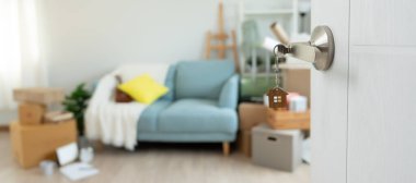 Taşınmak, taşınmak. Anahtar yeni evin kapısına yerleştirilmiş, odanın içinde kişisel eşyalar ve mobilyalar içeren bir karton kutu vardı. Daireye gir, afiş.