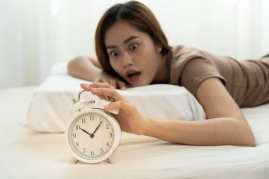 Shocked Asia young woman looking at clock alarm, lady is late appointment or work or class study, overslept, difficulty get up in mornings, time worried, not on time, sleepy, over due, Hurry up time