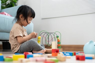 Mutlu Asyalı çocuk oyun oynuyor ve oyuncak bloklarını öğreniyor. Çocuklar evde çok mutlu ve heyecanlı. Çocuk oyun, etkinlik, gelişme ve dikkat eksikliği hiperaktivite bozukluğuyla çok iyi vakit geçiriyor