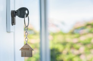 Evin kilidini açmak kapıya takılı. Kira ve satış için ikinci el ev. Anahtarlık rüzgarda savruluyor. Yeni ev için ipotek, satın alma, satma, yenileme, yatırım, sahip, emlak