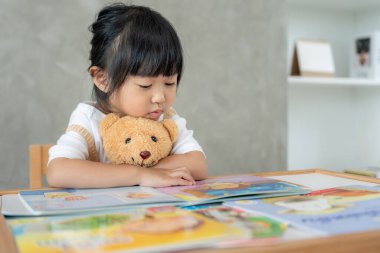 Mutlu Asyalı çocuklar rahatlayın ayı bebek için masal kitabı okuyun. Kızım ve bir hikaye okuyordum. öğrenim geliştirme, çocuk bakımı, eğitim, hikaye anlatma, uygulama, hayal etme, bağımlılığı azaltma cep telefonu