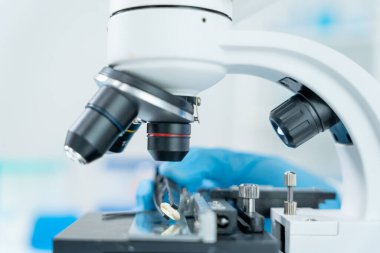 Bilimadamı ileri bilimsel laboratuvarda biyokimyasal örnekleri analiz ediyor. Tıbbi profesyonel kullanım mikroskobu virüsün mikrobiyolojik gelişimini gösteriyor. Fen laboratuvarında biyoteknoloji araştırması.