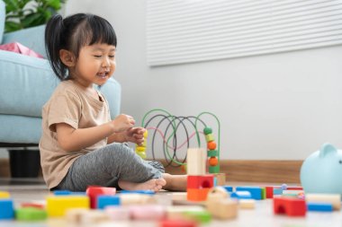 Mutlu Asyalı çocuk oyun oynuyor ve oyuncak bloklarını öğreniyor. Çocuklar evde çok mutlu ve heyecanlı. Çocuk oyun, etkinlik, gelişme ve dikkat eksikliği hiperaktivite bozukluğuyla çok iyi vakit geçiriyor