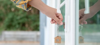 Evin kilidini açmak için ev sahibi anahtarı kapıya takılı. Kira ve satış için ikinci el ev. Sahibi el ile yeni ev için kapı ipoteğini açar, satın alır, satar, yeniler, yatırım, sahip, estat