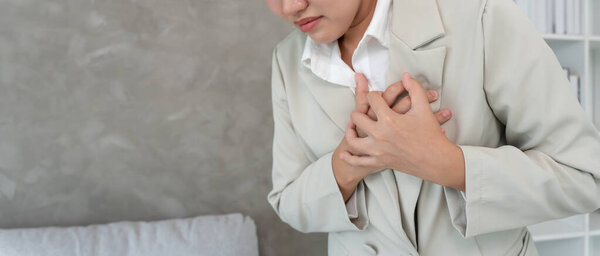 рука держать грудь с симптомами сердечного приступа, деловая женщина упорно работают есть боли в груди, вызванные болезнью сердца, утечка, расширение, увеличенное коронарное сердце, нажмите на грудь с болезненным выражением