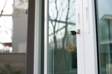 Landlord key for unlocking house is plugged into the door. Second hand house for rent and sale. keychain is blowing in the wind. mortgage for new home, buy, sell, renovate, investment, owner, estate