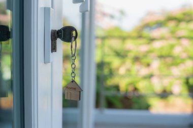 Landlord key for unlocking house is plugged into the door. Second hand house for rent and sale. keychain is blowing in the wind. mortgage for new home, buy, sell, renovate, investment, owner, estate