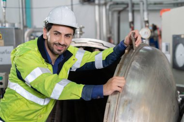 Portre mühendisleri veya güvenlik kaskı takan fabrika yöneticileri üretim hattındaki makineleri inceleyin. Müfettiş standardı karşılamak için sistemi test etmek için makineyi açtı. makine bakımı
