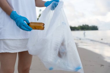 Su tasarrufu. Gönüllü olarak plajdaki çöpleri topluyor ve plastik şişeler suda yaşayan canlılara zarar gelmesini engelliyor. Dünya, Çevre, Yeşilci Gezegen, küresel ısınmayı azaltmak, Dünya 'yı kurtarmak