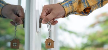 Evin kilidini açmak için ev sahibi anahtarı kapıya takılı. Kira ve satış için ikinci el ev. Sahibi el ile yeni ev için kapı ipoteğini açar, satın alır, satar, yeniler, yatırım, sahip, estat