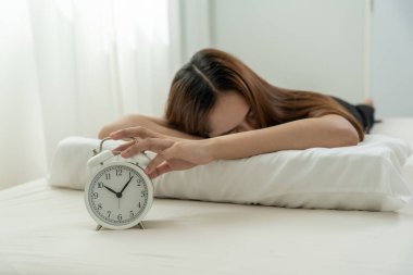 Tembel Asya 'lı genç kadın saat alarmını kapatıyor, bayan geç kalıyor ya da işe gidiyor ya da ders çalışıyor, uyuyakalıyor, sabahları uyanıyor, endişeleniyor, uykulu, geç kalmış, acele et.