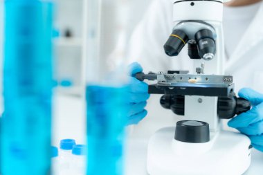 Bilimadamı ileri bilimsel laboratuvarda biyokimyasal örnekleri analiz ediyor. Tıbbi profesyonel kullanım mikroskobu virüsün mikrobiyolojik gelişimini gösteriyor. Fen laboratuvarında biyoteknoloji araştırması.