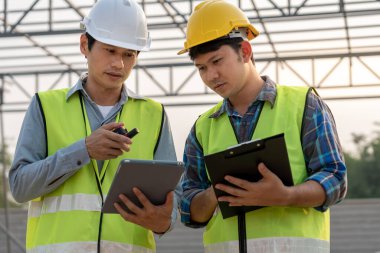 Mühendisler tablet kullanır ve bölgedeki planı kontrol ederler. Müteahhit ve müfettiş teftiş inşaatı sırasında. Sivil Forman kalite güvencesini kontrol ediyor. Denetim, teftiş, kalite denetimi.