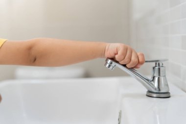 Su tasarrufu. Küçük çocuk çevreyi korumak için tuvaletteki suyu kapatıp duruyor. Yeşillenen gezegen, küresel ısınmayı azalt Dünya 'yı, yaşamı, geleceği, risk enerjisini, krizi, su gününü kurtar.