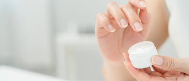 Güzel Asyalı kadın cilt kremini kontrol ediyor. Sağlıklı bir kadın yüzüne krem sürün ve makyaj yapın. Cilt kremi reklamı, kırışıklık önleyici, bebek yüzü, beyazlatma, nemlendirici.
