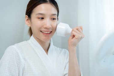 Güzel Asyalı kadınlar gözeneklerini sıkmak için aletler kullanır. Sağlıklı yüzler. Yüz bakımı ve tedavisi. Deri reklamı. Yüz kremi, kırışıklık önleyici, bebek yüzü, beyazlatma, nemlendirici, gözenek sıkılaştırıcı serum.