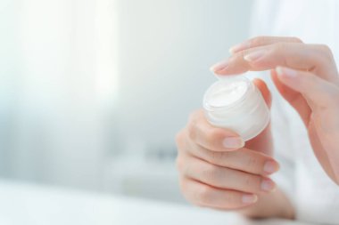 Kadın cilt kremini kontrol ediyor. Sağlıklı bir kadın yüzüne krem sürün ve makyaj yapın. Cilt kremi reklamı, kırışıklık önleyici, bebek yüzü, beyazlatma, nemlendirici.