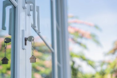 Landlord key for unlocking house is plugged into the door. Second hand house for rent and sale. keychain is blowing in the wind. mortgage for new home, buy, sell, renovate, investment, owner, estate