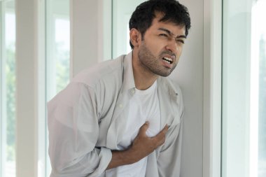 Göğüs kafesinde kalp krizi belirtileri var. Çok çalışan bir adamın göğüs ağrısı var. Kalp rahatsızlığı, sızıntı, genişleme, genişlemiş kalp, göğsüne acı veren bir ekspresyoyla bastırma.