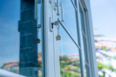  Evin kilidini açmak kapıya takılı. Kira ve satış için ikinci el ev. Anahtarlık rüzgarda savruluyor. Yeni ev için ipotek, satın alma, satma, yenileme, yatırım, sahip, mülk