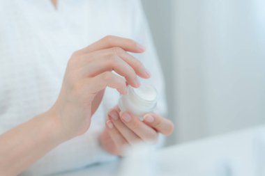 Güzel Asyalı kadın cilt kremini kontrol ediyor. Sağlıklı bir kadın yüzüne krem sürün ve makyaj yapın. Cilt kremi reklamı, kırışıklık önleyici, bebek yüzü, beyazlatma, nemlendirici.