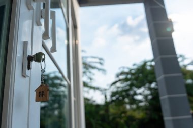 Landlord key for unlocking house is plugged into the door. Second hand house for rent and sale. keychain is blowing in the wind. mortgage for new home, buy, sell, renovate, investment, owner, estate