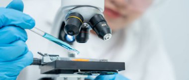 Bilimadamı ileri bilimsel laboratuvarda biyokimyasal örnekleri analiz ediyor. Tıbbi profesyonel kullanım mikroskobu virüsün mikrobiyolojik gelişimini gösteriyor. Fen laboratuvarında biyoteknoloji araştırması.