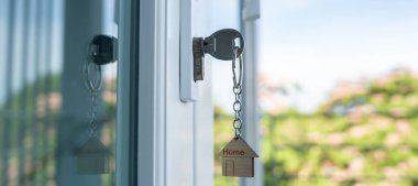 Landlord key for unlocking house is plugged into the door. Second hand house for rent and sale. keychain is blowing in the wind. mortgage for new home, buy, sell, renovate, investment, owner, estate