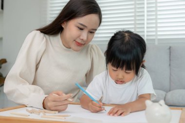 Mutlu Asyalı anne küçük kız için boya öğreniyor. Komik aile evde mutlu ve heyecanlı. Anne ve kızı birlikte vakit geçiriyorlar. Tatil, etkinleştir