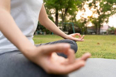 Kadın parkta meditasyon yapıyor. Sabahları egzersiz yapan Asyalı bir kadın. denge, dinlenme, rahatlama, sakinlik, sağlık, mutluluk, rahatlama, sağlıklı yaşam tarzı, stresi azaltma, huzur, tutum.