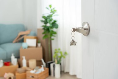 Moving house, relocation. The key was inserted into the door of the new house, inside the room was a cardboard box containing personal belongings and furniture. move in the apartment or condominium