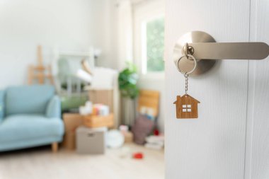 Moving house, relocation. The key was inserted into the door of the new house, inside the room was a cardboard box containing personal belongings and furniture. move in the apartment or condominiu