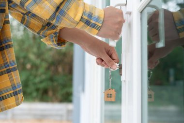 Evin kilidini açmak için ev sahibi anahtarı kapıya takılı. Kira ve satış için ikinci el ev. Sahibi el ile yeni ev için kapı ipoteğini açar, satın alır, satar, yeniler, yatırım, sahip, estat