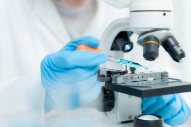 Bilimadamı ileri bilimsel laboratuvarda biyokimyasal örnekleri analiz ediyor. Tıbbi profesyonel kullanım mikroskobu virüsün mikrobiyolojik gelişimini gösteriyor. Fen laboratuvarında biyoteknoloji araştırması.