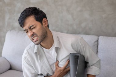 Göğüs kafesinde kalp krizi belirtileri var. Çok çalışan bir adamın göğüs ağrısı var. Kalp rahatsızlığı, sızıntı, genişleme, genişlemiş kalp, göğsüne acı veren bir ekspresyoyla bastırma.