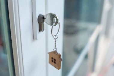 Landlord key for unlocking house is plugged into the door. Second hand house for rent and sale. keychain is blowing in the wind. mortgage for new home, buy, sell, renovate, investment, owner, estate