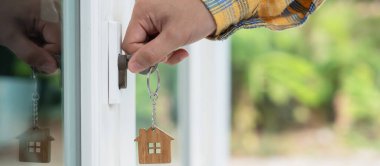 Evin kilidini açmak için ev sahibi anahtarı kapıya takılı. Kira ve satış için ikinci el ev. Sahibi el ile yeni ev için kapı ipoteğini açar, satın alır, satar, yeniler, yatırım, sahip, estat