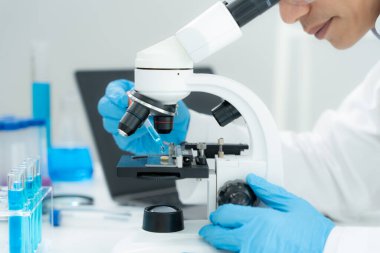 Bilimadamı ileri bilimsel laboratuvarda biyokimyasal örnekleri analiz ediyor. Tıbbi profesyonel kullanım mikroskobu virüsün mikrobiyolojik gelişimini gösteriyor. Fen laboratuvarında biyoteknoloji araştırması