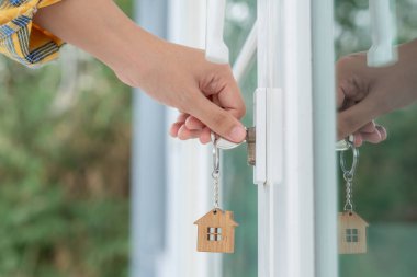 Evin kilidini açmak için ev sahibi anahtarı kapıya takılı. Kira ve satış için ikinci el ev. Sahibi el ile yeni ev için kapı ipoteğini açar, satın alır, satar, yeniler, yatırım, sahip, estat
