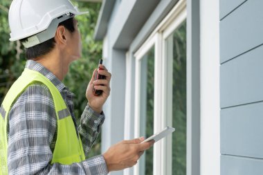inspector or engineer is inspecting construction and quality assurance new house using a checklist. Engineers or architects or contactor work to build the house before handing it over to the homeowner