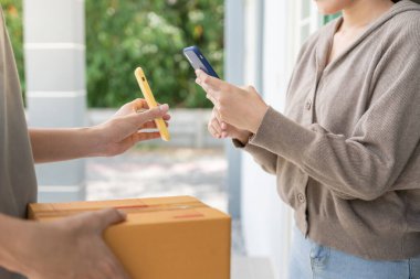Mutlu bir gülümseme Asyalı kadın yemek parası için QR kodunu tarıyor. Teslimatçı ekspres teslimat gönderdi. Çevrimiçi dükkan, kağıt konteynır, paket servis, paket, elektronik para, dijital transfer