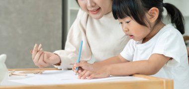 Mutlu Asyalı anne küçük kız için boya öğreniyor. Komik aile evde mutlu ve heyecanlı. Anne ve kızı birlikte vakit geçiriyorlar. Tatil, etkinleştir