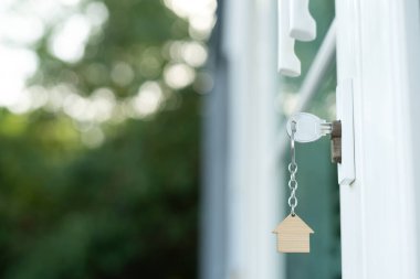 Evin kilidini açmak kapıya takılı. Kira ve satış için ikinci el ev. Anahtarlık rüzgarda savruluyor. Yeni ev için ipotek, satın alma, satma, yenileme, yatırım, sahip, mülk