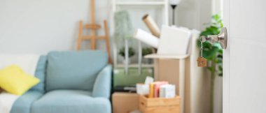 Moving house, relocation. The key was inserted into the door of the new house, inside the room was a cardboard box containing personal belongings and furniture. move in the apartment or condominium