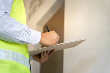 inspector or engineer is inspecting construction and quality assurance new house using a checklist. Engineers or architects or contactor work to build the house before handing it over to the homeowner