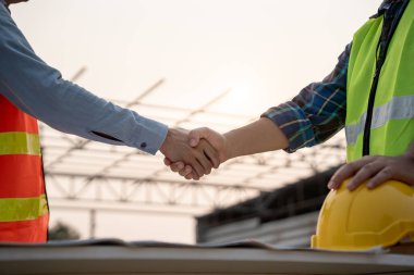 İnşaat ekibi el sıkışıyor. Başlangıç planı. İnşaat alanı, endüstri, mimari, ortak, takım çalışması, anlaşma, mülkiyet, irtibat merkezindeki yeni proje sözleşmesi.