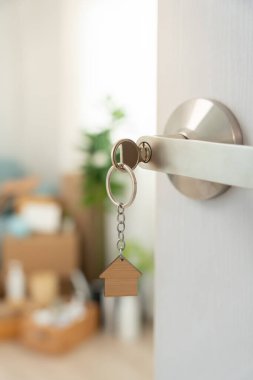 Moving house, relocation. The key was inserted into the door of the new house, inside the room was a cardboard box containing personal belongings and furniture. move in the apartment or condominium